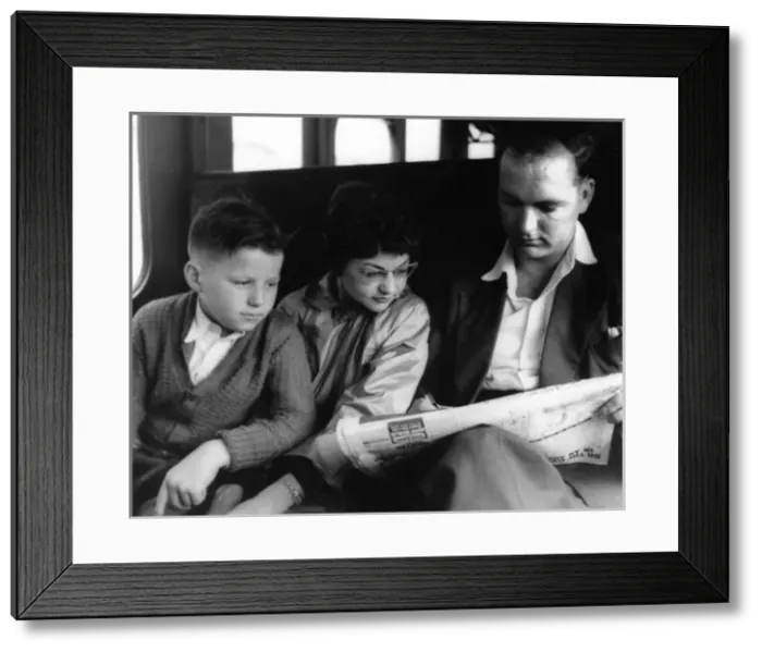 Framed Print : Man and two children doing the crossword on a train Framed Print : Man and two children doing the crossword on a train