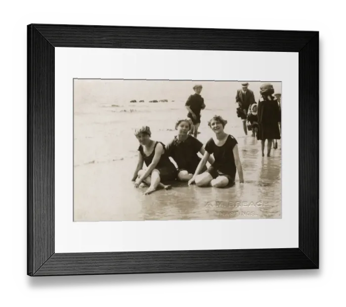 Framed Print : Three girls sitting in the surf at Hastings, Kent