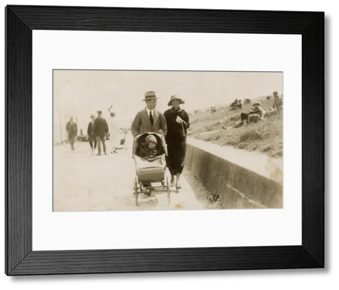 Framed Print : Couple strolling along the seafront with toddler in buggy Framed Print : Couple strolling along the seafront with toddler in buggy