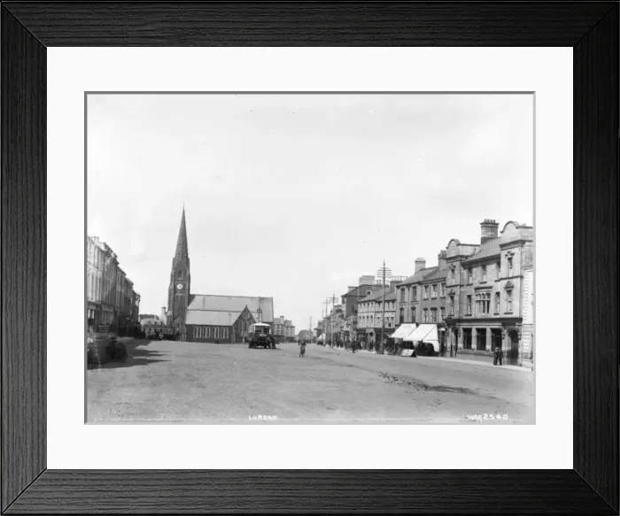 Framed Print : Lurgan - a street scene with motor bus and people and shop fronts and church Framed Print : Lurgan - a street scene with motor bus and people and shop fronts and church
