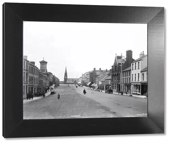 Lurgan - a street scene with motor car and people and shop fronts and church