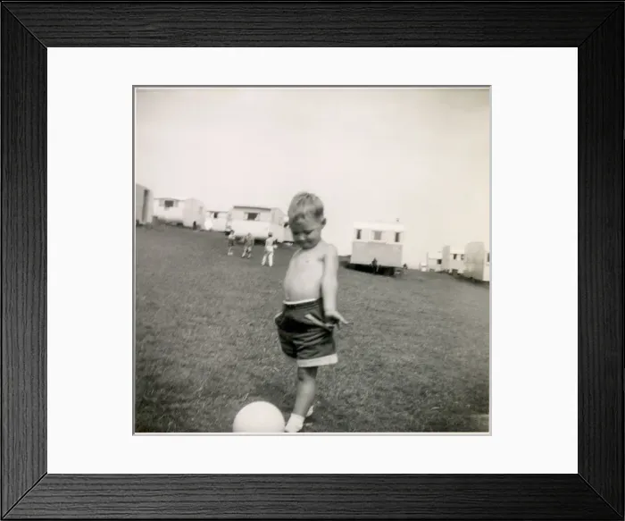 Framed Print : Young boy plays with a football at a holiday camp Framed Print : Young boy plays with a football at a holiday camp