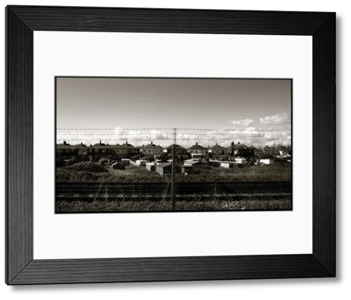Framed Print : Chain link fence and houses by railway Framed Print : Chain link fence and houses by railway