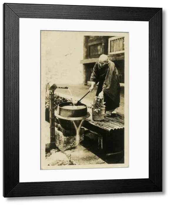 Framed Print : A Japanese man watering his flowers from a water pump Framed Print : A Japanese man watering his flowers from a water pump