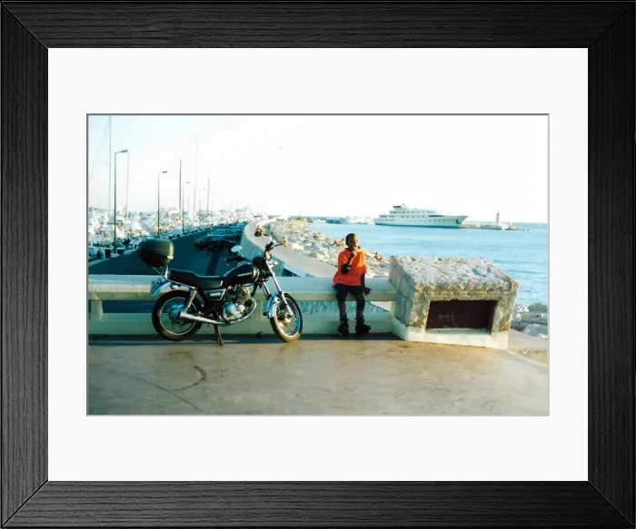 Framed Print : British Caribbean Heritage - Boy sitting by a motor bike in Framed Print : British Caribbean Heritage - Boy sitting by a motor bike in