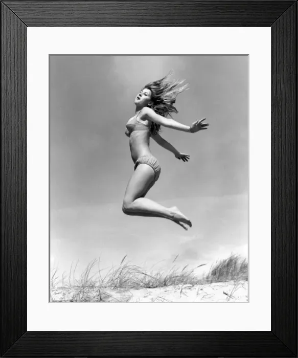 Framed Print : Young woman leaps up from a sand dune, Cornwall Framed Print : Young woman leaps up from a sand dune, Cornwall