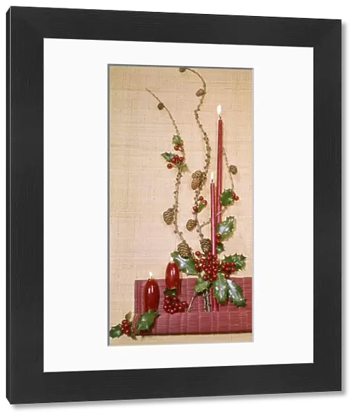 Christmas arrangement of candles, holly and pine cones