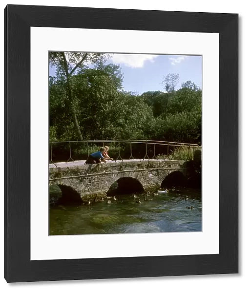 Two boys on a bridge, feeding ducks, Bibury, Gloucestershire