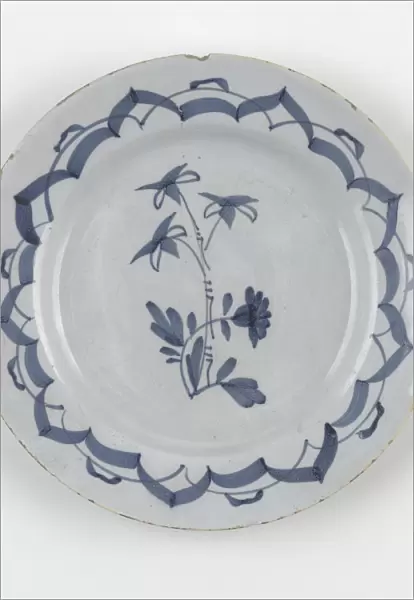Plate. Tin-glazed earthenware plate painted in blue with a central floral stem