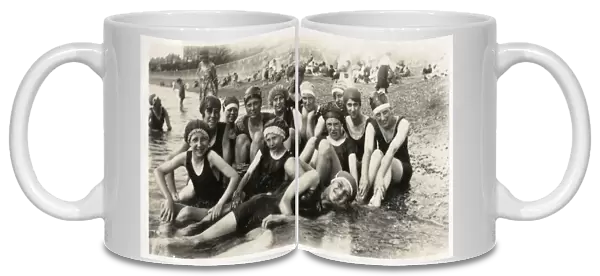 Thirteen seaside bathers in swimming costumes and caps