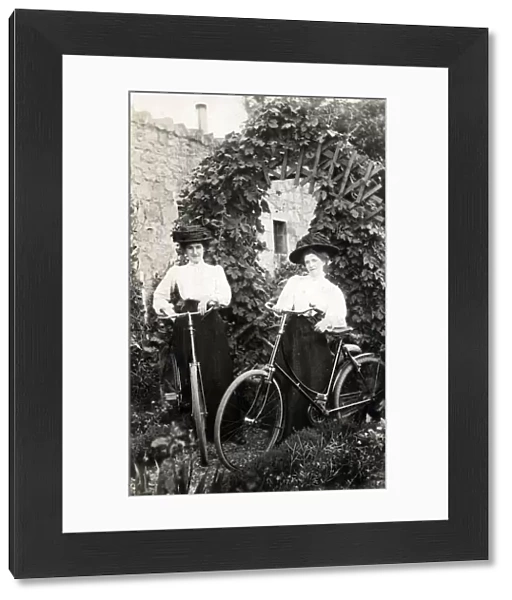 Two Edwardian women with their bicycles in a garden