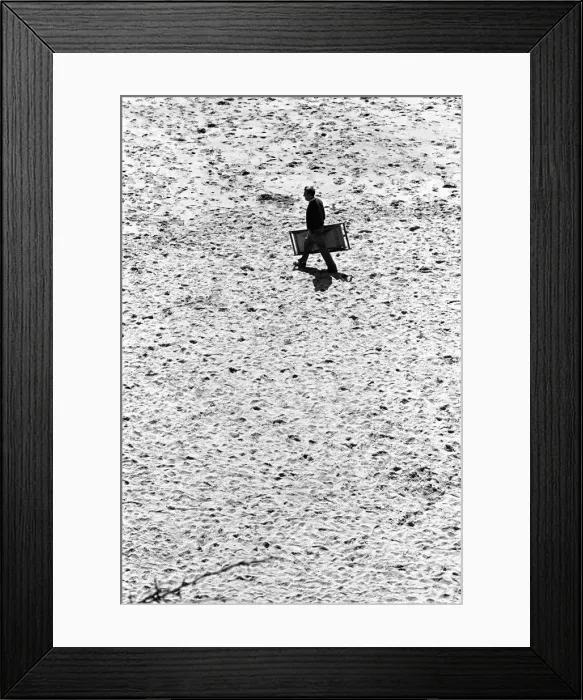 Framed Print : Man walks across Tenby beach carrying a deck chair Framed Print : Man walks across Tenby beach carrying a deck chair