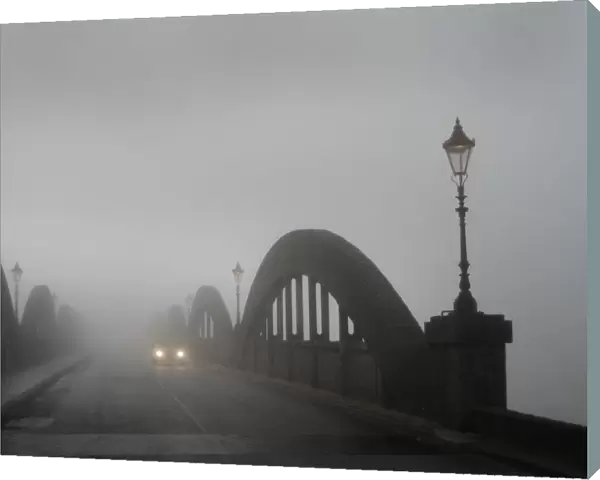 A car in thick fog on the concrete bridge over the River Dee