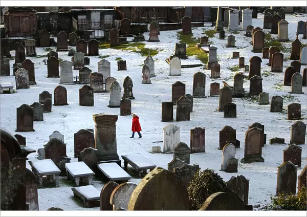 Woman in red coat in Kirkcudbright snowy graveyard