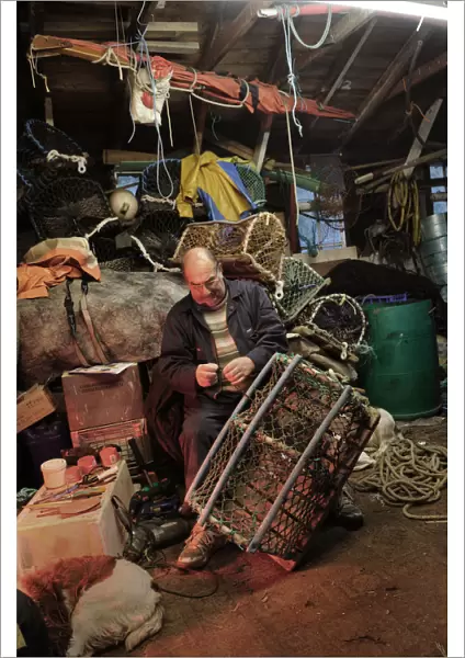 A fisherman mends a lobster pot in his waterside shed