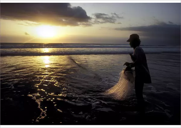 A Balinese fisherman pauses to look at the sunset