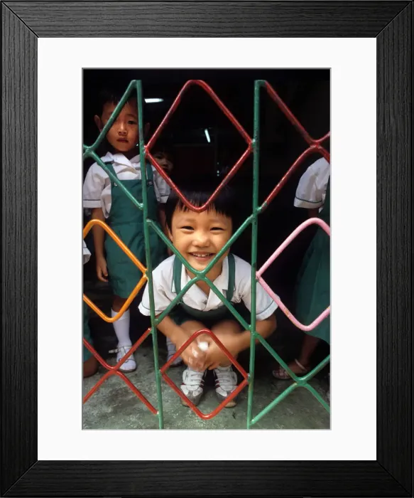 Framed Print : A small child behind the grill of a kindergarten, Hong Kong Framed Print : A small child behind the grill of a kindergarten, Hong Kong