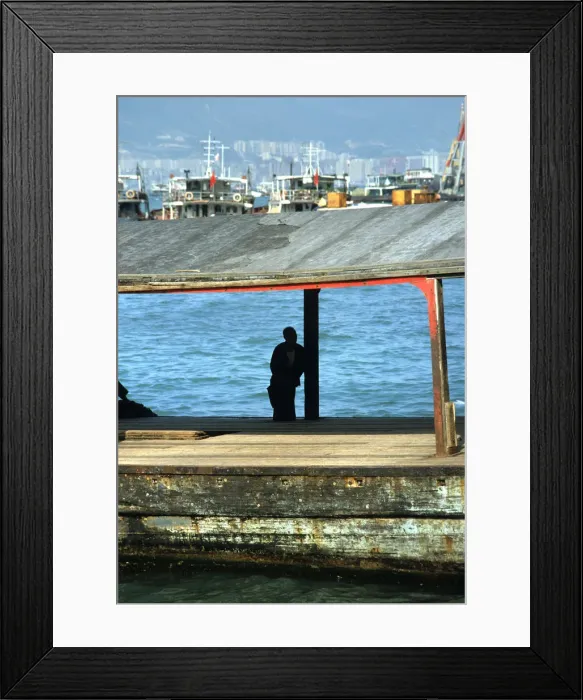 Framed Print : Silhouette of man sat on a bollard on a pier in Hong Kong Framed Print : Silhouette of man sat on a bollard on a pier in Hong Kong