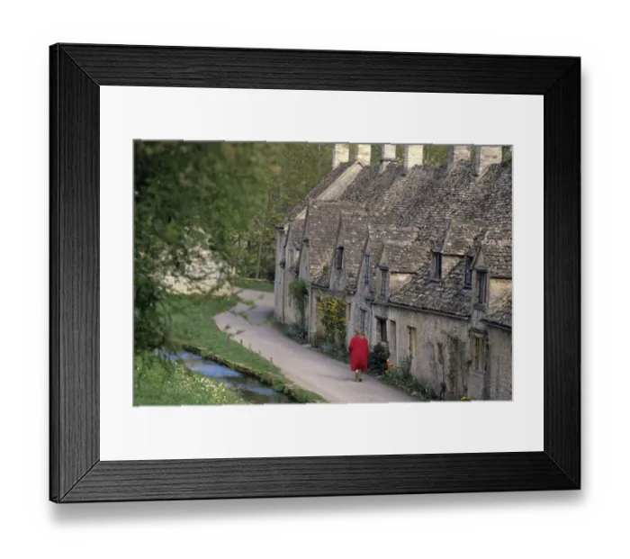 Framed Print : A woman walks past stone cottages in the village of Bilbury Framed Print : A woman walks past stone cottages in the village of Bilbury