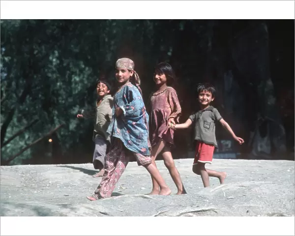 Four happy Kashmir children run along banks of River Jhelum