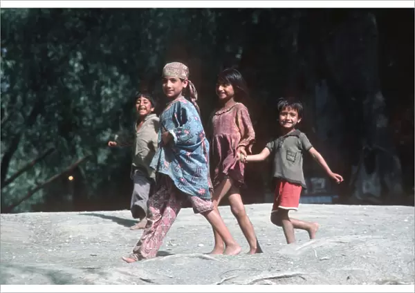 Four happy Kashmir children run along banks of River Jhelum