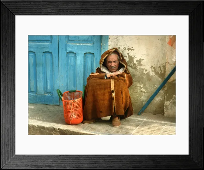 Framed Print : Old man wearing a djelleba sits on pavement, Tunisia Framed Print : Old man wearing a djelleba sits on pavement, Tunisia