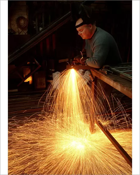 A steelworker makes a shower of sparks in his workshop