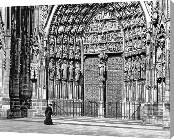 Priest walking in front of Strasbourg Cathedral, France