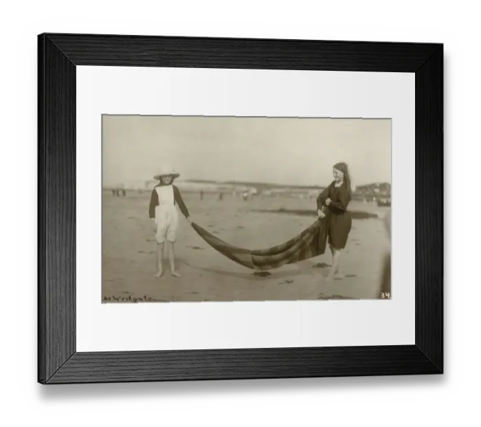 Framed Print : Two Girls folding up a striped blanket on the beach at Westgate-on-Sea in northeast Kent