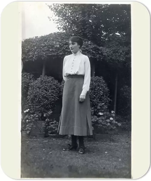 A female student (?) posing for a photograph in a suburban garden. circa 1910s