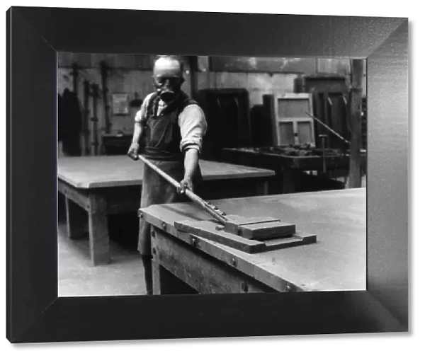 A workman smoothing the surface of the slate bed of a billiard table at a factory in