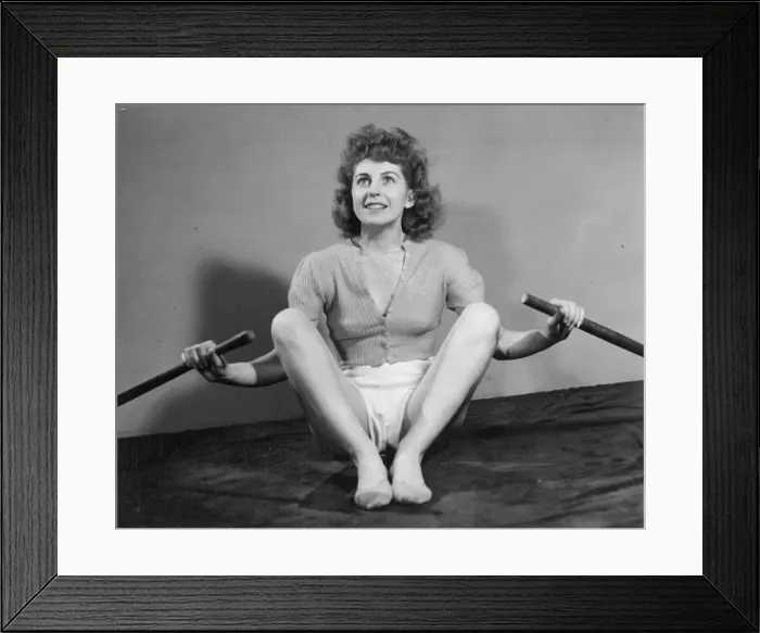 Framed Print : A young woman exercising with a pair of oars. Date: 1940s Framed Print : A young woman exercising with a pair of oars. Date: 1940s