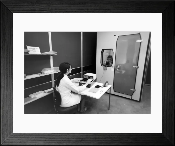 Framed Print : Biomedical centre, London -- a woman operates a machine while a patient in a locked room