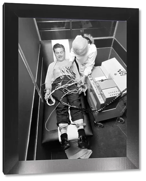 Biomedical centre, London -- a woman attaches sensors to a patient. Date: 1972