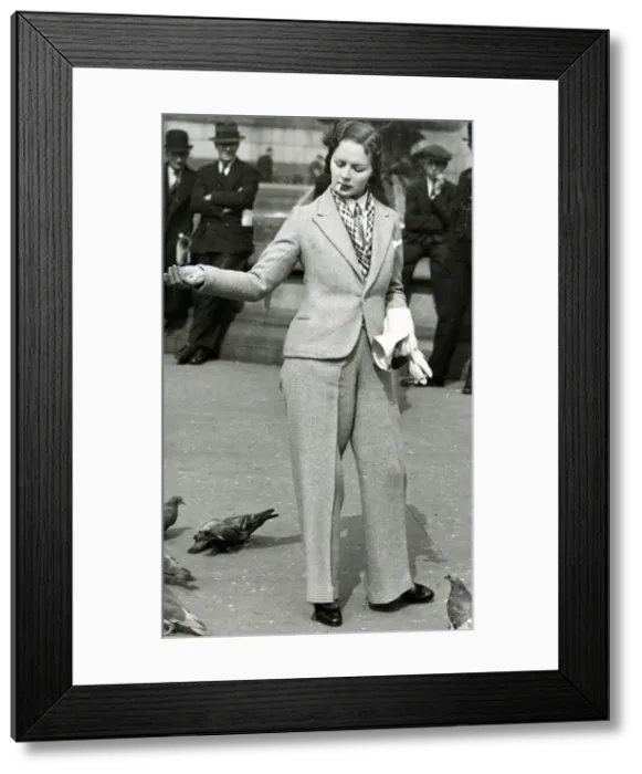 Framed Print : Woman in trouser suit feeding pigeons, Trafalgar Square Framed Print : Woman in trouser suit feeding pigeons, Trafalgar Square