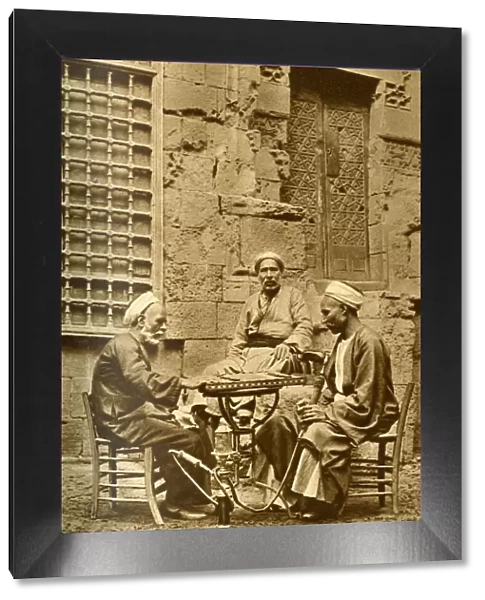 Men playing game of draughts in a courtyard, Egypt