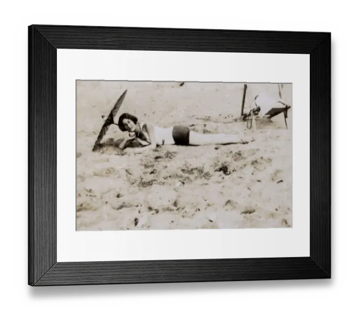 Framed Print : Woman sunbathing underneath a parasol on the beach Framed Print : Woman sunbathing underneath a parasol on the beach