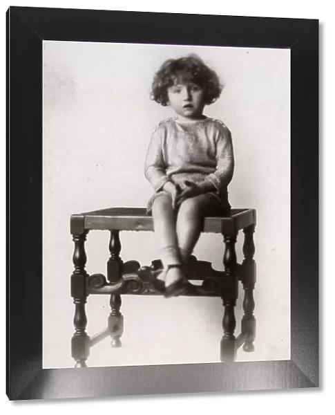 A Little girl photographed on a turned wooden stool