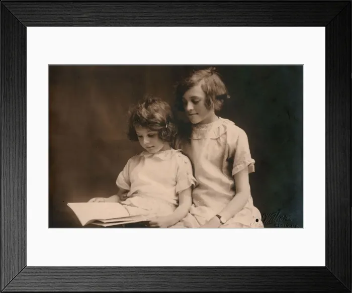 Framed Print : Older girl helps her younger sister read a book Framed Print : Older girl helps her younger sister read a book