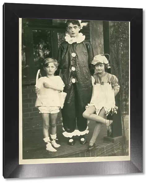 Three children in fancy dress, as cupid, a clown or pierrot