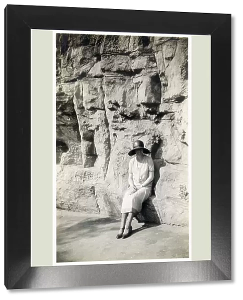 Lady sitting on a natural seat beneath a rock cliff