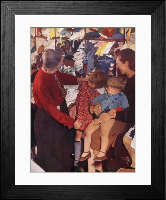 Framed Print : A W. V. S. worker selecting a frock for a little girl Framed Print : A W. V. S. worker selecting a frock for a little girl