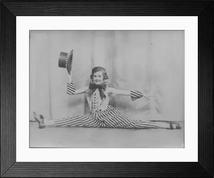 Framed Print : A little girl does the splits in a jolly stage costume of striped trousers and top hat Framed Print : A little girl does the splits in a jolly stage costume of striped trousers and top hat