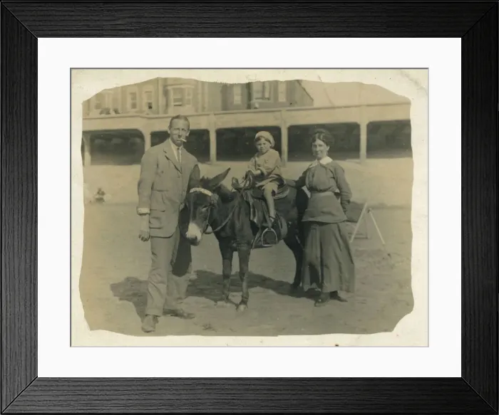 Framed Print : A small child goes for a donkey ride on the beach at an unidentified British seaside Framed Print : A small child goes for a donkey ride on the beach at an unidentified British seaside