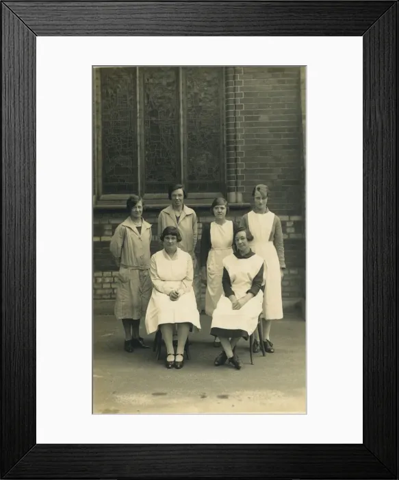 Framed Print : Group of six women, wearing aprons or overalls. They look as if they are staff at a Framed Print : Group of six women, wearing aprons or overalls. They look as if they are staff at a