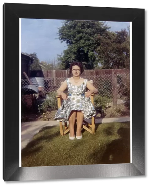 Woman sitting in garden chair - neat suburban garden