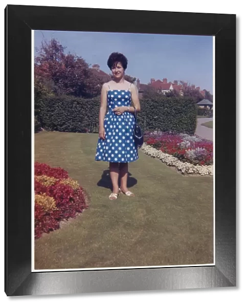 Young lady standing between beautifully-manicured flowerbeds