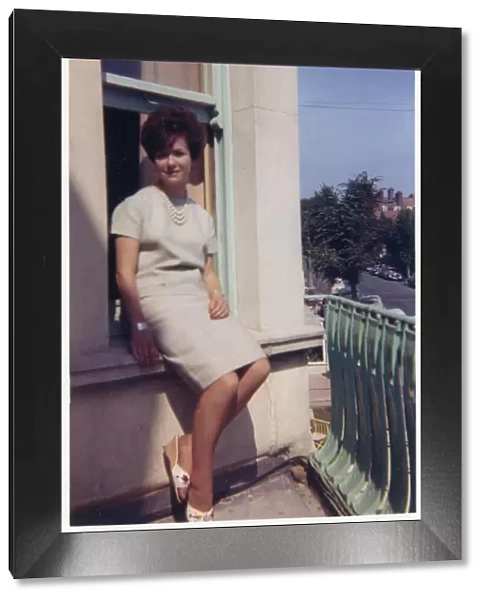 Young lady seated on exterior window ledge - seaside hotel