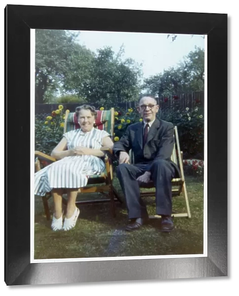 A jolly older couple in a neat suburban back garden