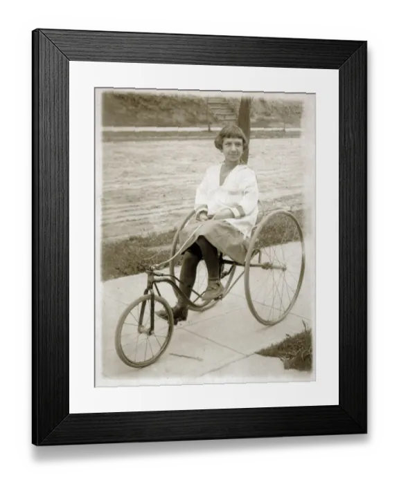 Framed Print : Girl riding a vintage peddle tricycle along the sidewalk Framed Print : Girl riding a vintage peddle tricycle along the sidewalk